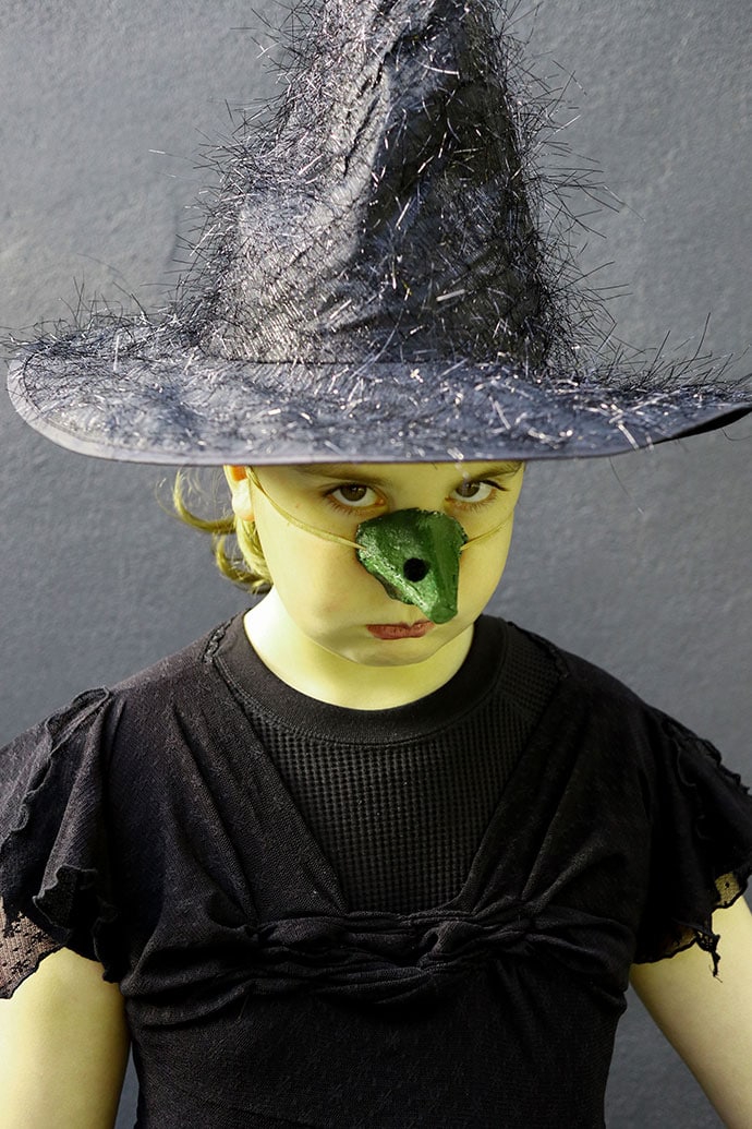 Girl with green face in witch costume