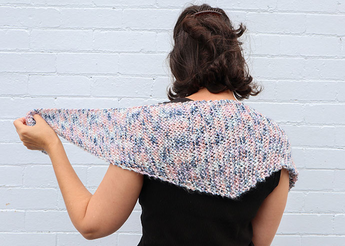 woman wearing knitted triangle shawl over shoulders. 