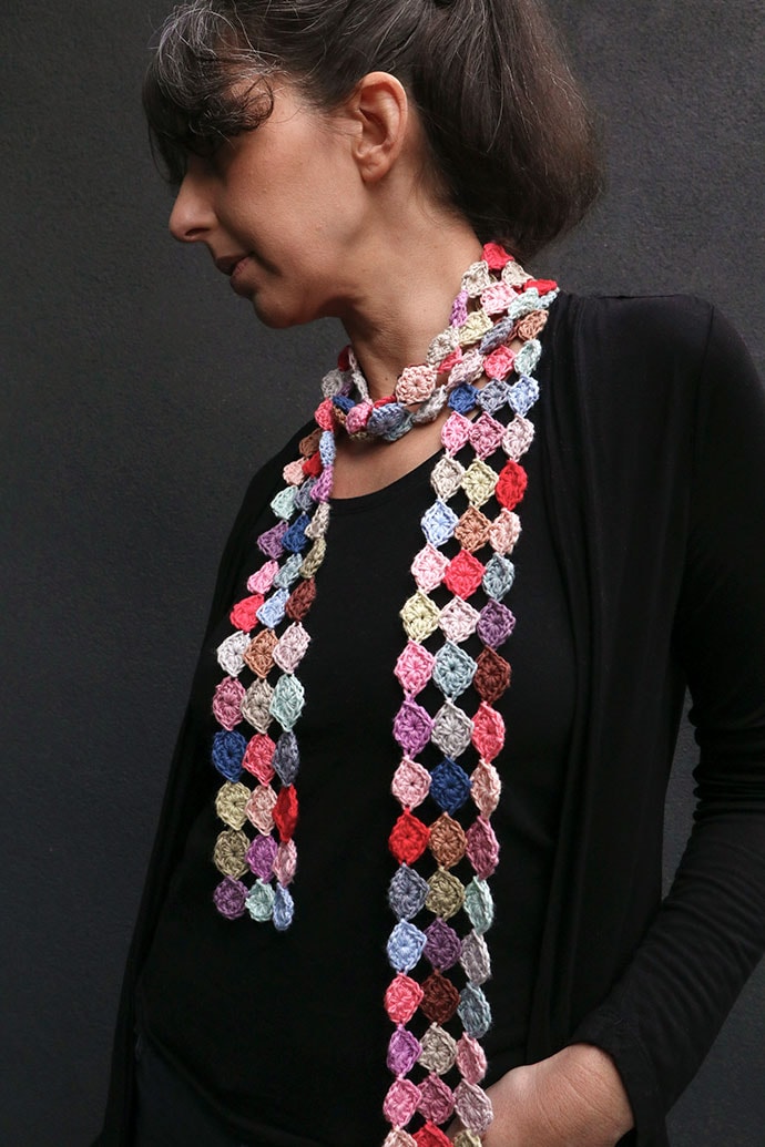 confetti scarf corchet pattern - woman dressed in black wearing spotty crochet scarf
