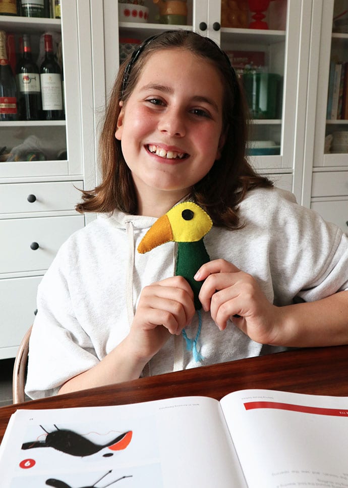 girl holding a handmade toucan toy