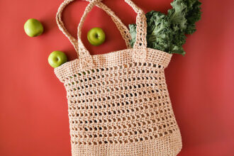 Crochet bag laying flat with apples and kale spilling out